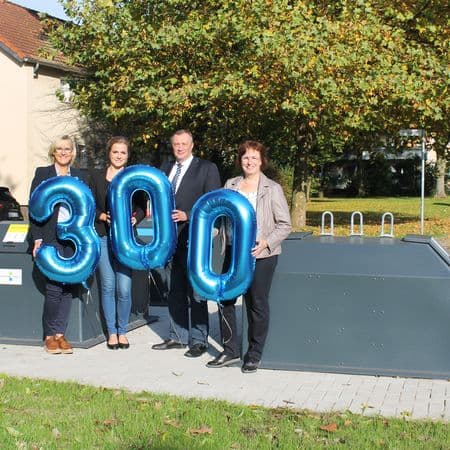 Vier Personen stehen mit der Luftballonzahl 300 vor zwei Haibunterflurbehältern