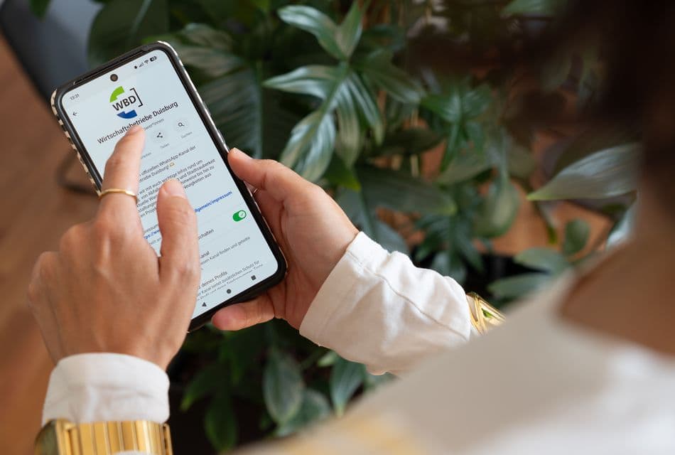 Frau schaut auf ein Smartphone mit WhatsApp-Kanal.