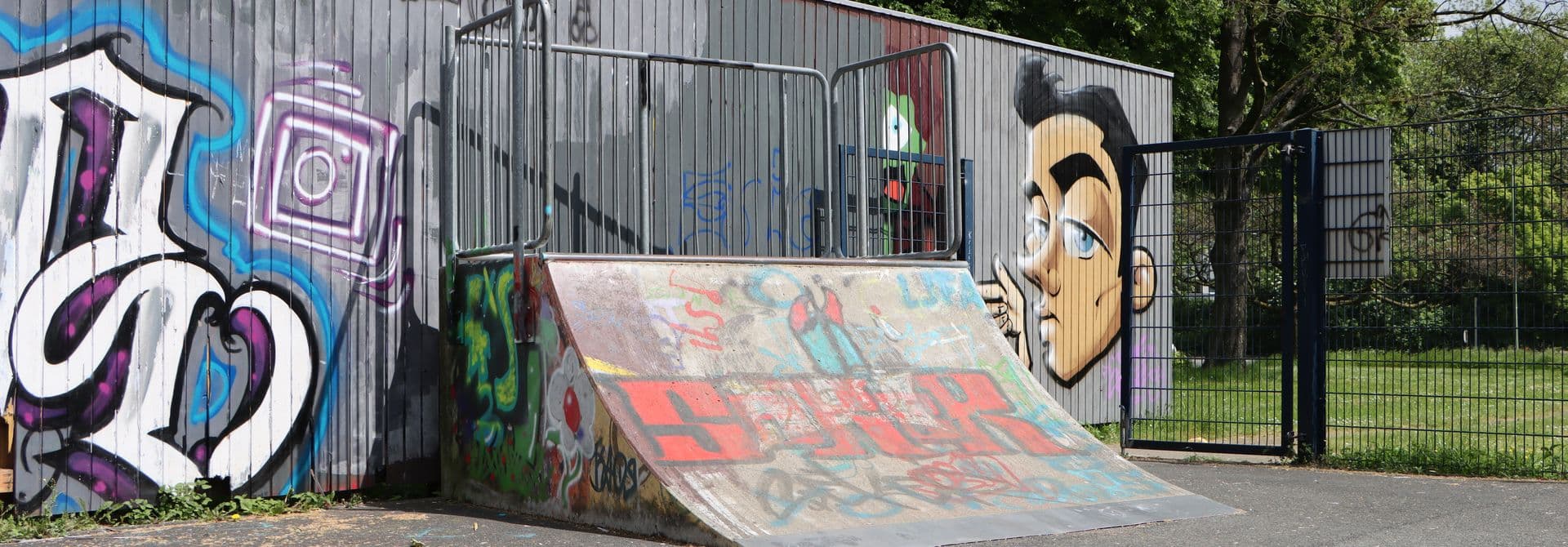 Rampe in einem Skatepark, im Hintergrund Graffitti