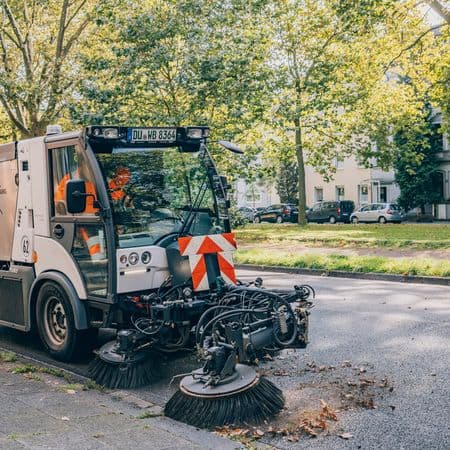 Kehrmaschine auf der Straße, die den Straßenrand reinigt
