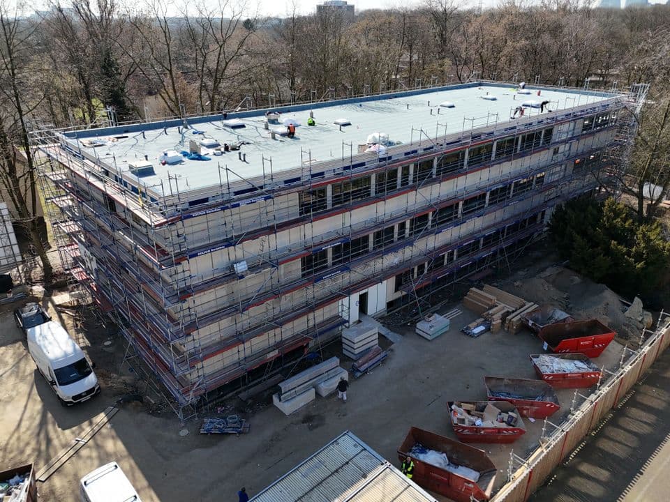 Der Erweiterungsneubau der Gesamtschule Walsum an der Kurze Straße nimmt Gestalt an: In modularer Bauweise wurde der Rohbau des dreigeschossigen Gebäudes innerhalb von nur drei Wochen fertiggestellt – Etage für Etage. Bereits während der Modulstellung begann der Innenausbau, der bereits sichtbare Fortschritte zeigt. Die Fenster sind montiert, Dachabdichtungen werden bald abgeschlossen, und auch Elektro-, Lüftungs- und Heizungsinstallationen laufen planmäßig.