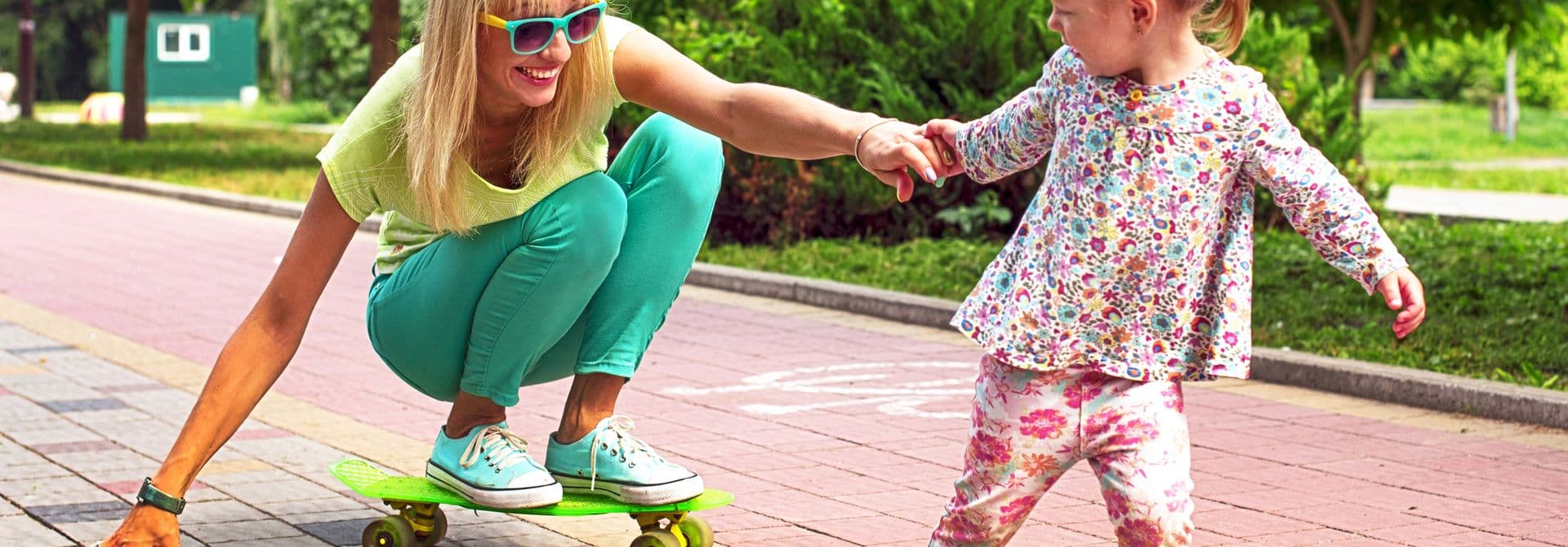 Spielplatzshutterstock_2291064973 Mutter mit Kind auf einem Skateboard