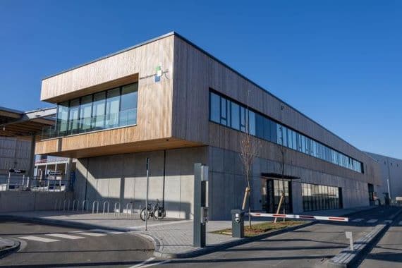 Recyclingzentrum Mitte Das Recyclingzentrum Mitte, ein großes Gebäude mit Holzvertäfelung oben und Fensterreihen.