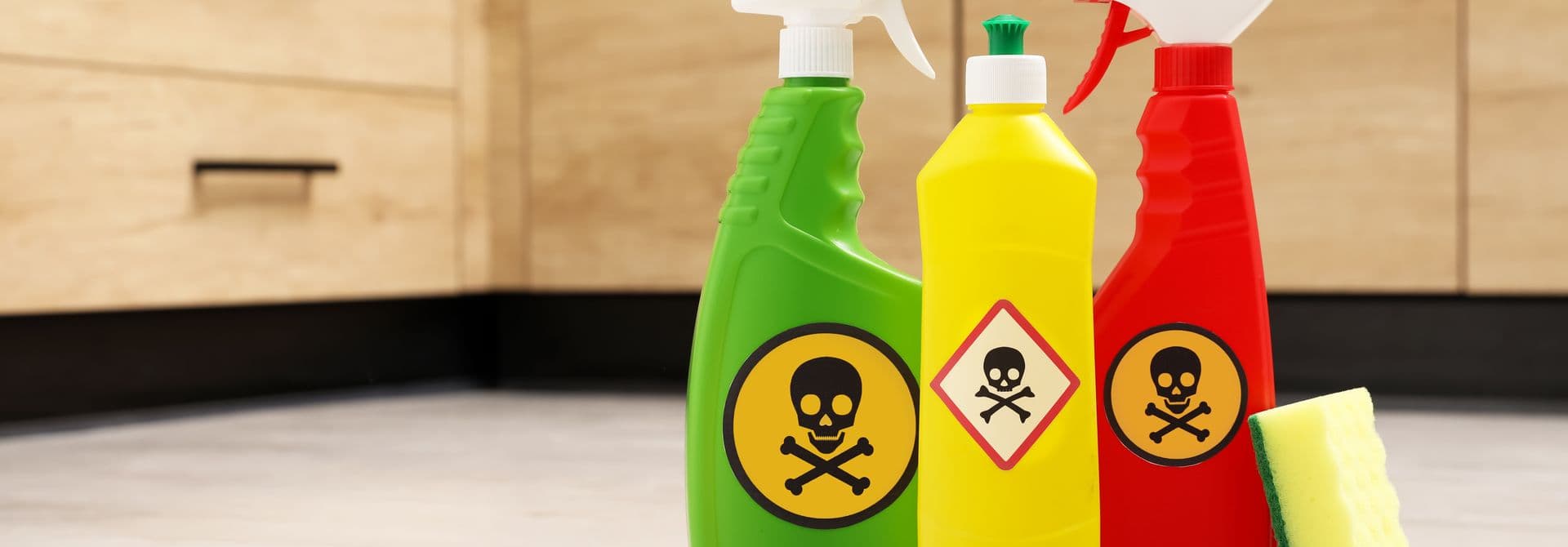 Schadstoffe Drei Kunststoffflaschen mit Totenkopf-Schadstoffzeichen stehen in einer Küche auf dem Boden.