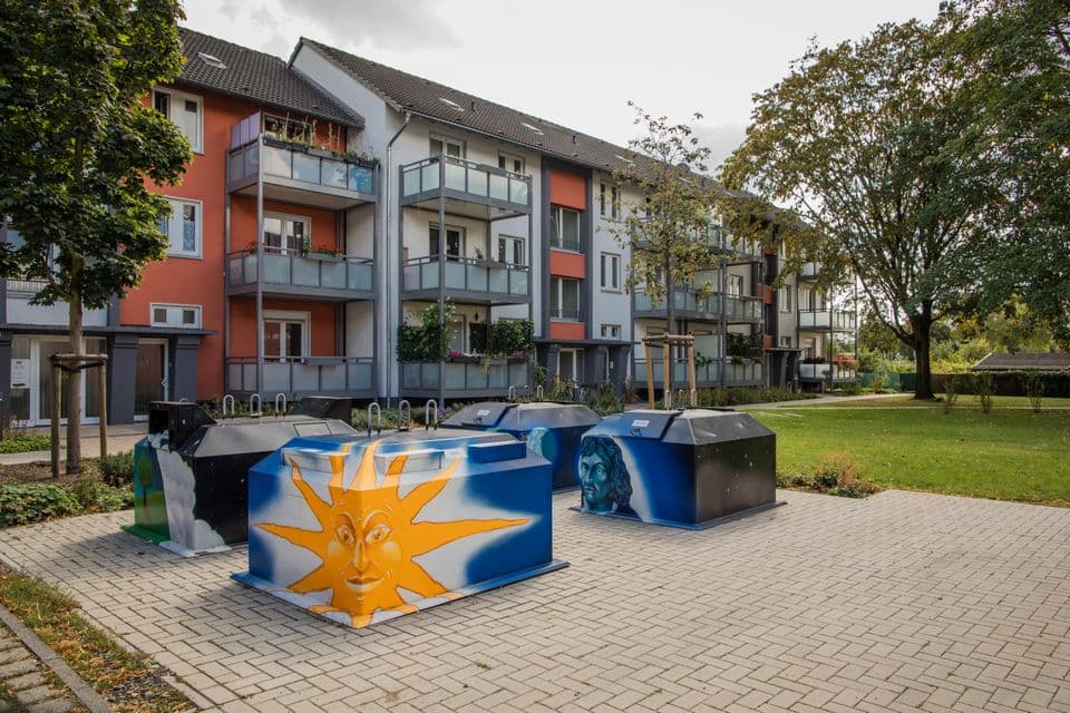 Halbunterflurbehälter Vier Halbunterflurbehälter mit individueller Lackierung vor einem Wohnhaus