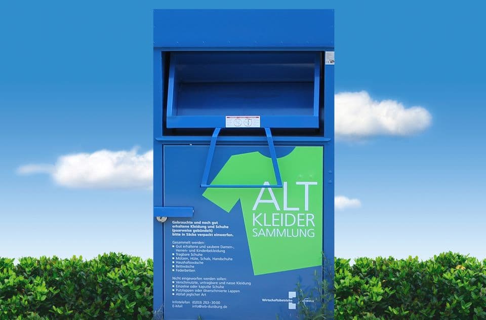 Altkleidercontainer Altkleidercontainer, dahinter Hecke und blauer Himmel