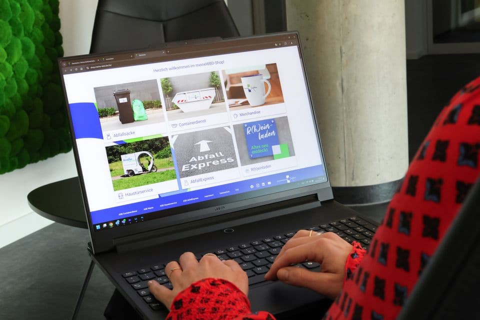 meineWBD-Shop Frau schaut auf Notebook. Dort sieht man den Webshop